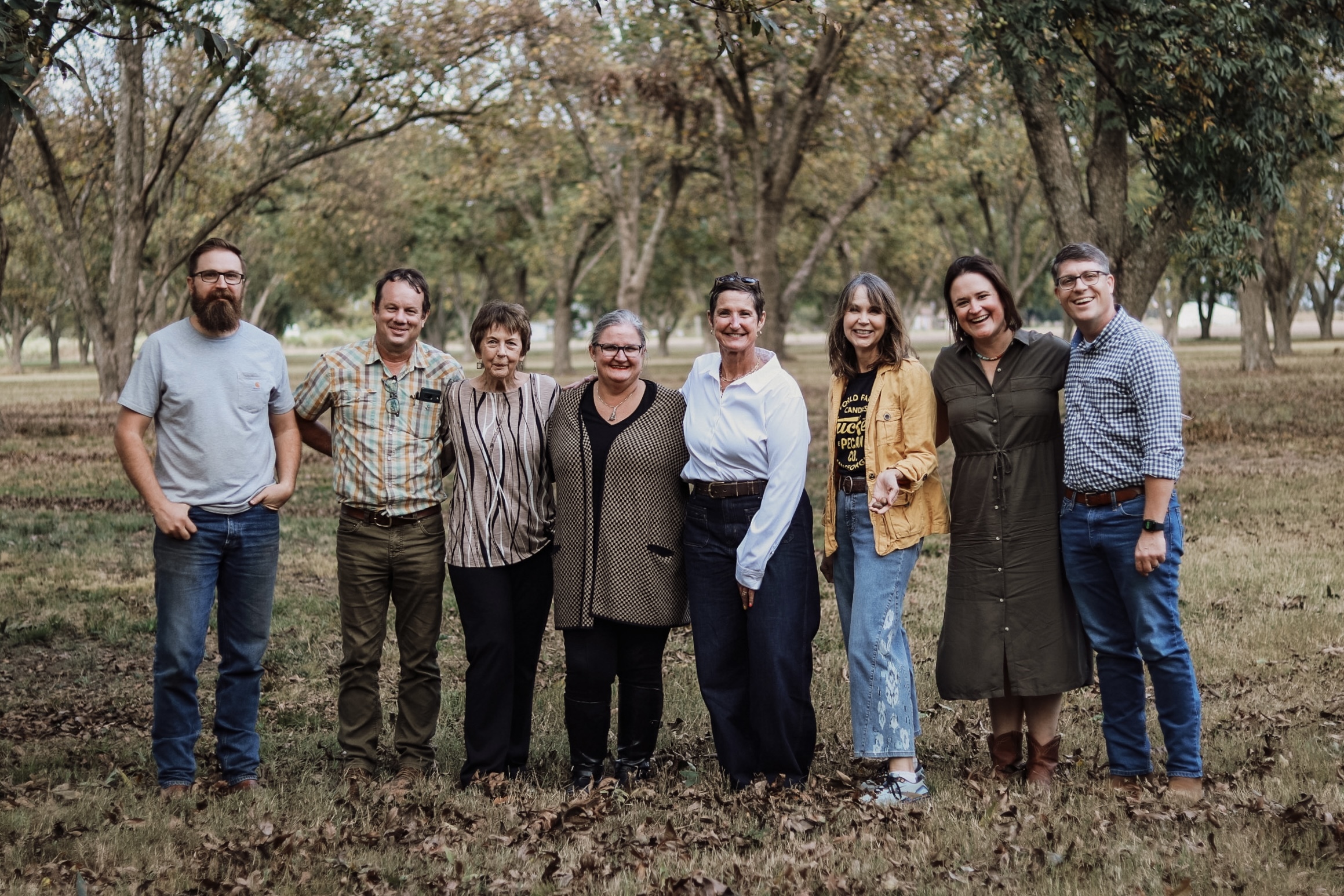A group of local leaders standing together in a pecan grove