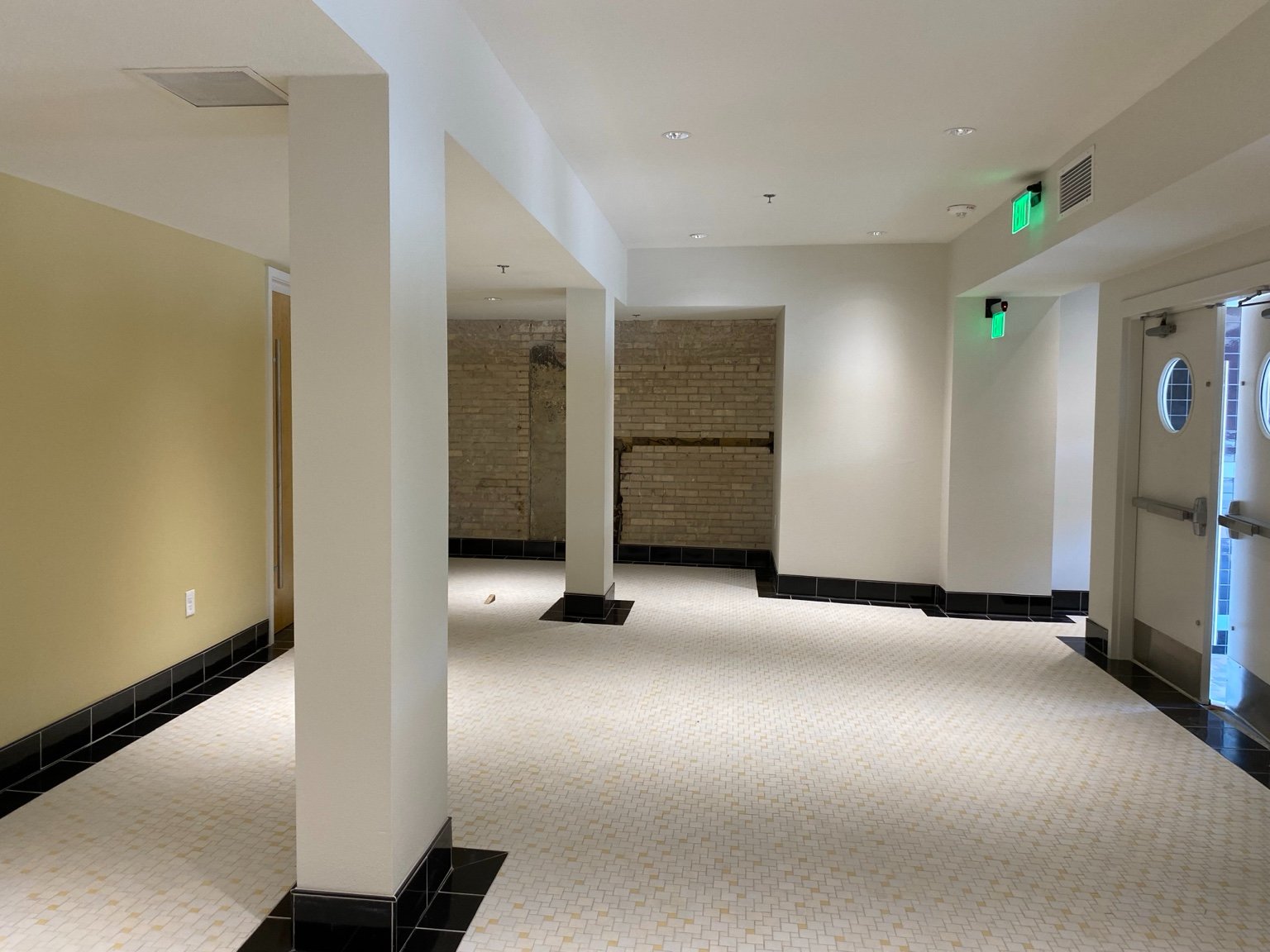 The renewed lobby with terrazzo-pattern tile floor and exposed historic brick
