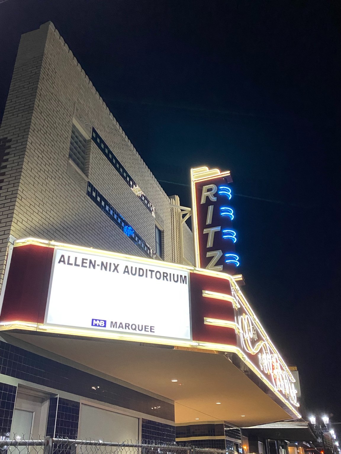 The re-created neon RITZ sign lit at night above the marquee