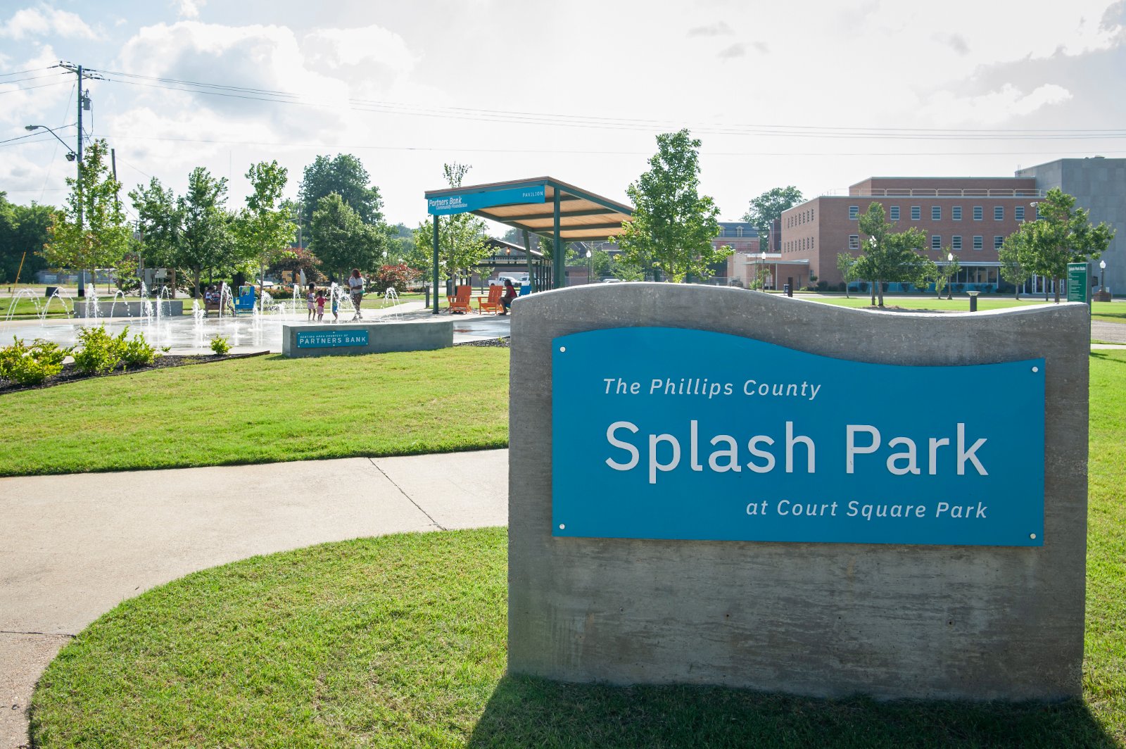 The Phillips County Splash Park at Court Square Park identity sign, a blue panel on a curved concrete base